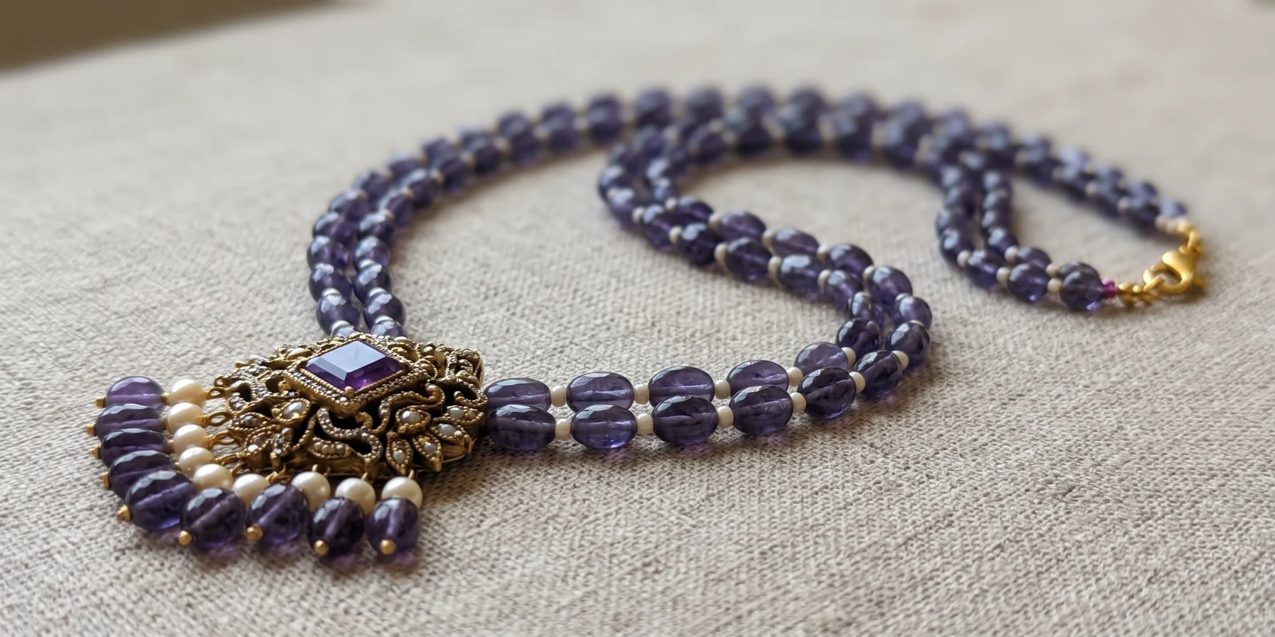 Amethyst Elegance with its purple beads and ornate pendant resting on linen
